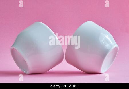 Two white ceramic cups without handles on a pink background Stock Photo