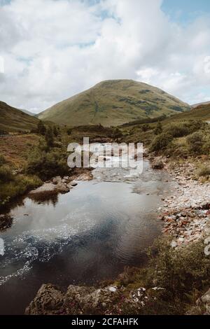 Picturesque landscape of mountain and cloudy sky reflected in tranquil water in Glencoe on daytime Stock Photo