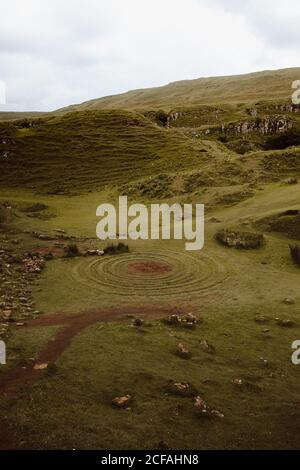 Mountain valley covered with green grass and mysterious spiral labyrinth made of stones in Fairy Glen Stock Photo