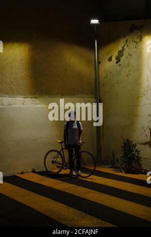 unrecognizable man with a bike at night in a parking illuminated with a streetlight Stock Photo