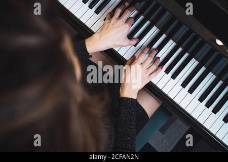 Top view of anonymous Woman musician playing on piano in room Stock Photo