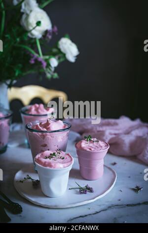 tasty glasses of strawberry mousse on a table with spoon near and decorated with flowers Stock Photo