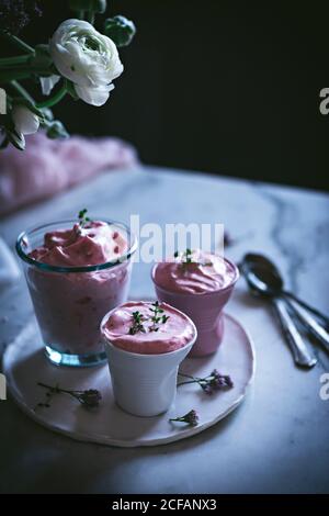 tasty glasses of strawberry mousse on a table with spoon near and decorated with flowers Stock Photo