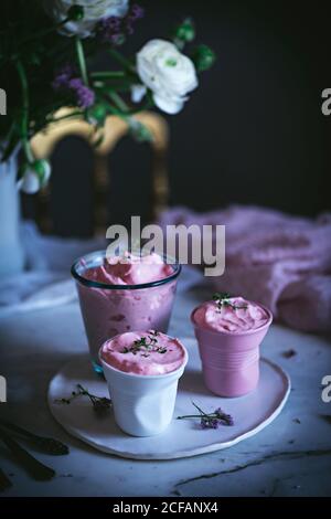 tasty glasses of strawberry mousse on a table with spoon near and decorated with flowers Stock Photo
