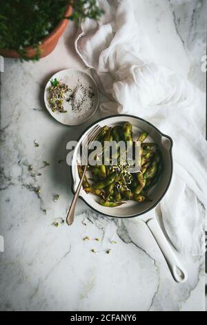 Top view of bowl with prepared immature soybeans placed on marble table near cloth napkin and seasonings Stock Photo