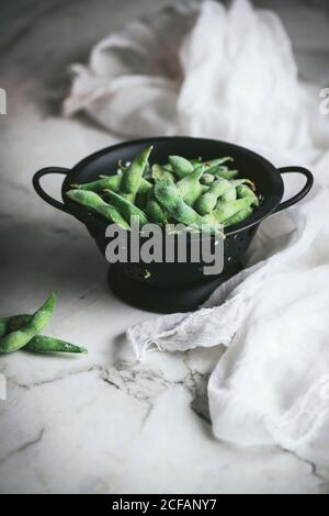 Strainer with uncooked edamames on the table Stock Photo