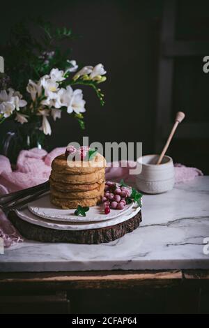 Stack of raspberry pancakes with fresh berry on porcelain plate at marble tabletop text to case with flowers over dark background Stock Photo
