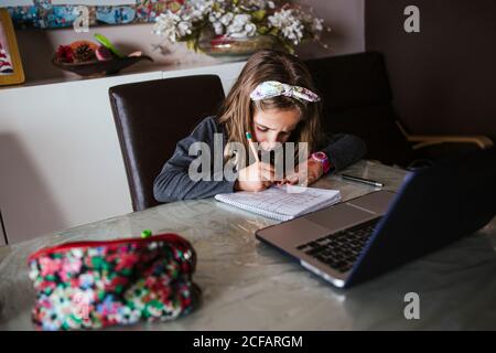 girl doing homework assignment from laptop Stock Photo