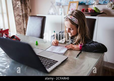 girl doing homework assignment from laptop Stock Photo
