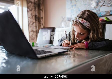 girl doing homework assignment from laptop Stock Photo