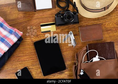 View of a variety of essential travelling items with tablet, smartphone and camera on wooden table Stock Photo