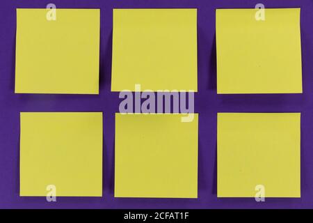 View of six yellow sheets of paper in one size on a plain purple background Stock Photo
