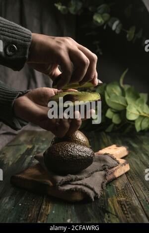 anonymous person hands cutting avocados in half to prepare guacamole Stock Photo