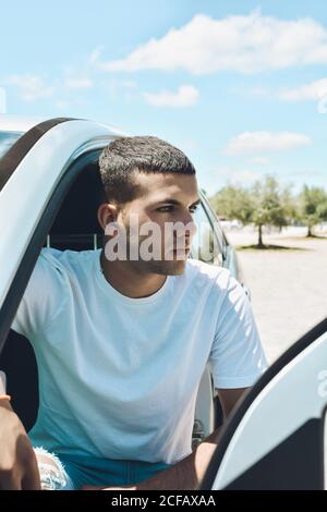 Young blue-eyed man and modern clothes getting off his car Stock Photo