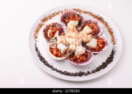 Mixed seafood platter (Scallops with tomato salsa and shrimp) served with purple and Black salt. Isolated on white background. Stock Photo