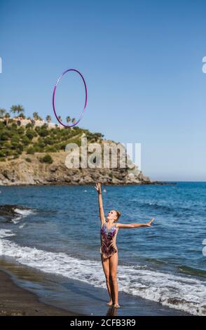 Graceful acrobat performs with hoop on beach Stock Photo