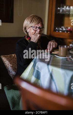 From above aged Woman having breakfast while sitting at table Stock Photo