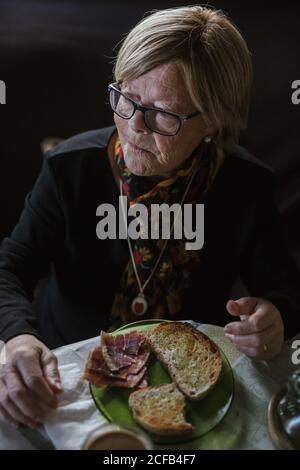 From above aged Woman having breakfast while sitting at table Stock Photo