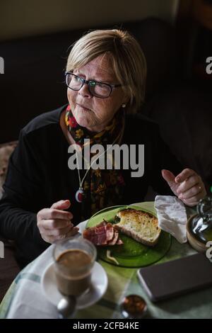 From above aged Woman having breakfast while sitting at table Stock Photo