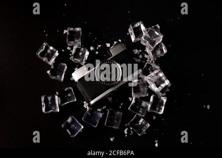 Top view of vintage photo camera surrounded by ice cubes showing concept of well preserved gadget on black background Stock Photo