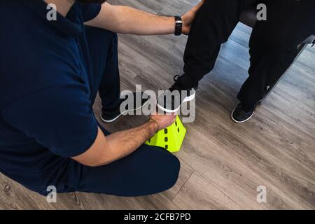 Senior lady during exercise with trainer using equipment in gym Stock Photo