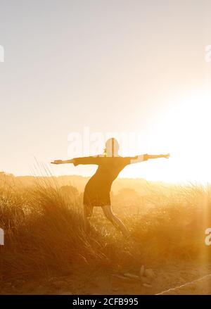 Young Woman posing between meadow with dry grass and blue sky with sun Stock Photo