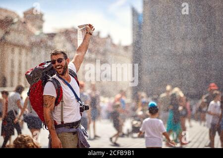 Young male tourist enjoying the fontaine shower and the city landmarks on a beautiful weather Stock Photo