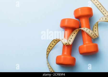 Dumbbells and measuring tape on blue background with copy space, top view Stock Photo