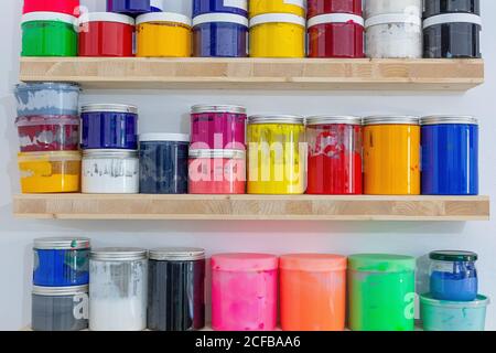 Shelves with colorful tins of paint of different shape size and colour at workplace Stock Photo