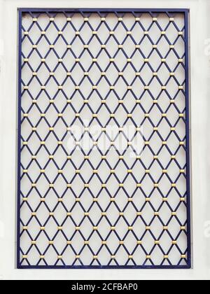 Decorative panel on the wall in the form of a black lattice with a diamond pattern and gold elements at the joints Stock Photo