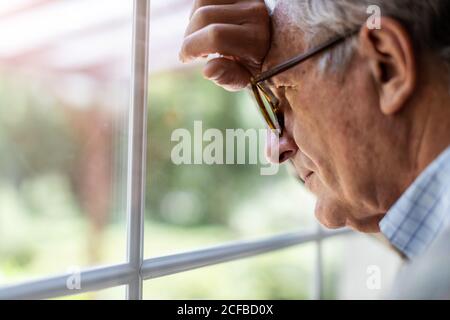 Senior man looking out of window at home Stock Photo