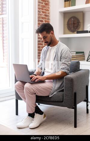 Bearded ethnic man using laptop while working on remote project at home Stock Photo