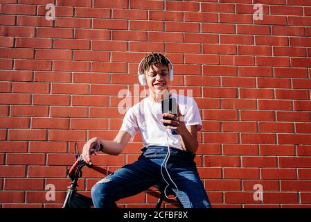 Young happy black male listening music with smartphone on bike Stock Photo