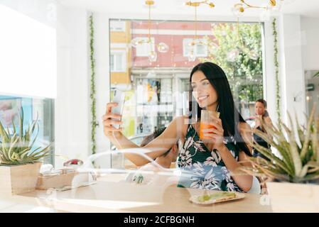 Lady with healthy drink taking selfie in cafe Stock Photo