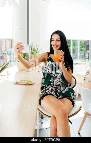 Lady with healthy drink taking selfie in cafe Stock Photo