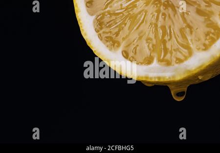Juicy slice of yellow lemon with a drop of juice. Stock Photo