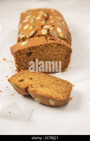 Close up slices of pumpkin bread with pumpkin puree, cinnamon, nutmeg and seeds, placed on white background. Stock Photo
