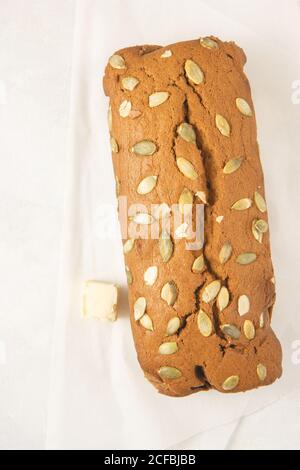 Fresh homemade pumpkin bread with pumpkin puree, cinnamon, nutmeg and seeds, isolated on white background, photographed overhead. Stock Photo