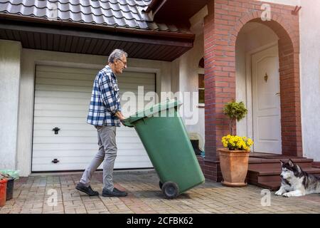 Senior man taking out garbage Stock Photo