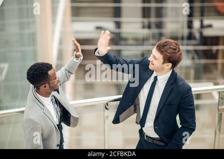 Celebrating success. Two young multiethnic businessmen giving each other high-five, celebrate great deal Stock Photo