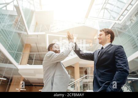 Celebrating success. Two young multiethnic businessmen giving each other high-five, celebrate great deal Stock Photo