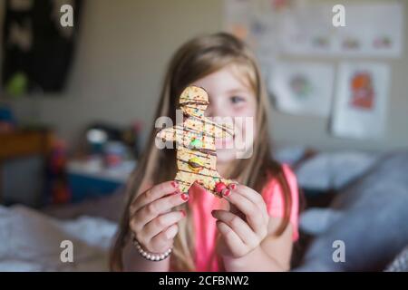 Young girl holding a gingerbread man sitting in her bedroom Stock Photo
