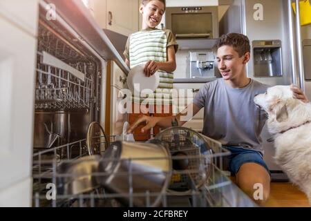 Two boys loading the dishwasher together at home Stock Photo