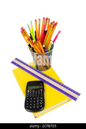 Vertical photograph of a rainbow color of pencils in pencil holder, with brightly colored yellow book, ruler and calculator. Isolated on a white backg Stock Photo