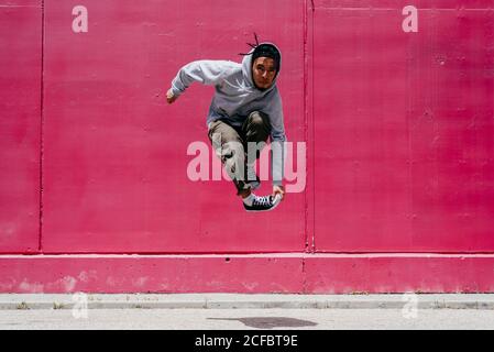 Young hispanic men jumping near to a pink wall on the street Stock Photo