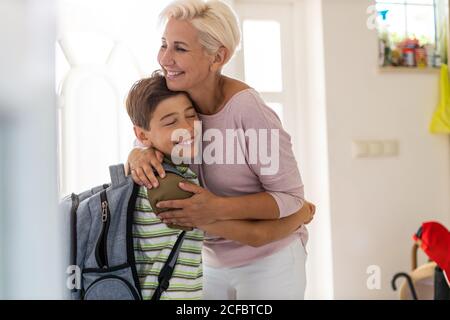 Mother and son with backpack in entrance hall Stock Photo