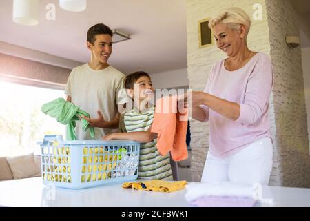 Two boys helping mother folding laundry in the living room Stock Photo