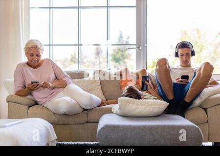 Family sitting on sofa using smartphones Stock Photo