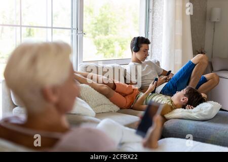 Family sitting on sofa using smartphones Stock Photo