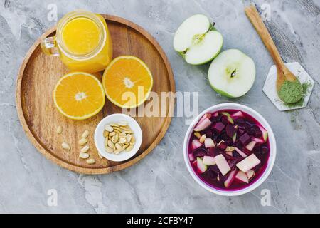 From above served oranges peanuts and orange juice on table with apples condiment and bowl of beets and apples Stock Photo
